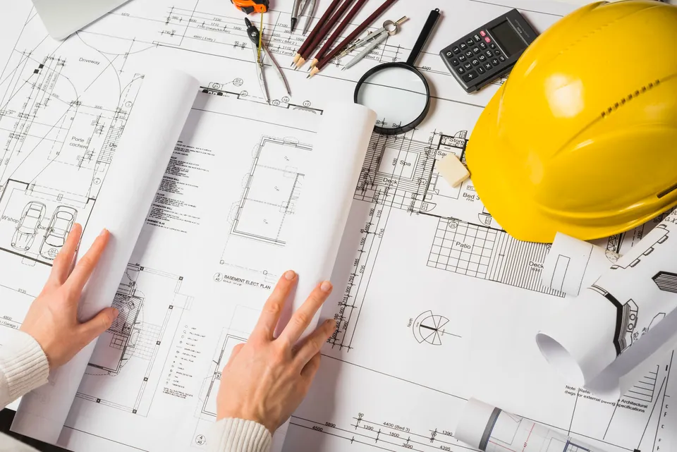 Drawings and a safety helmet on a construction estimating desk